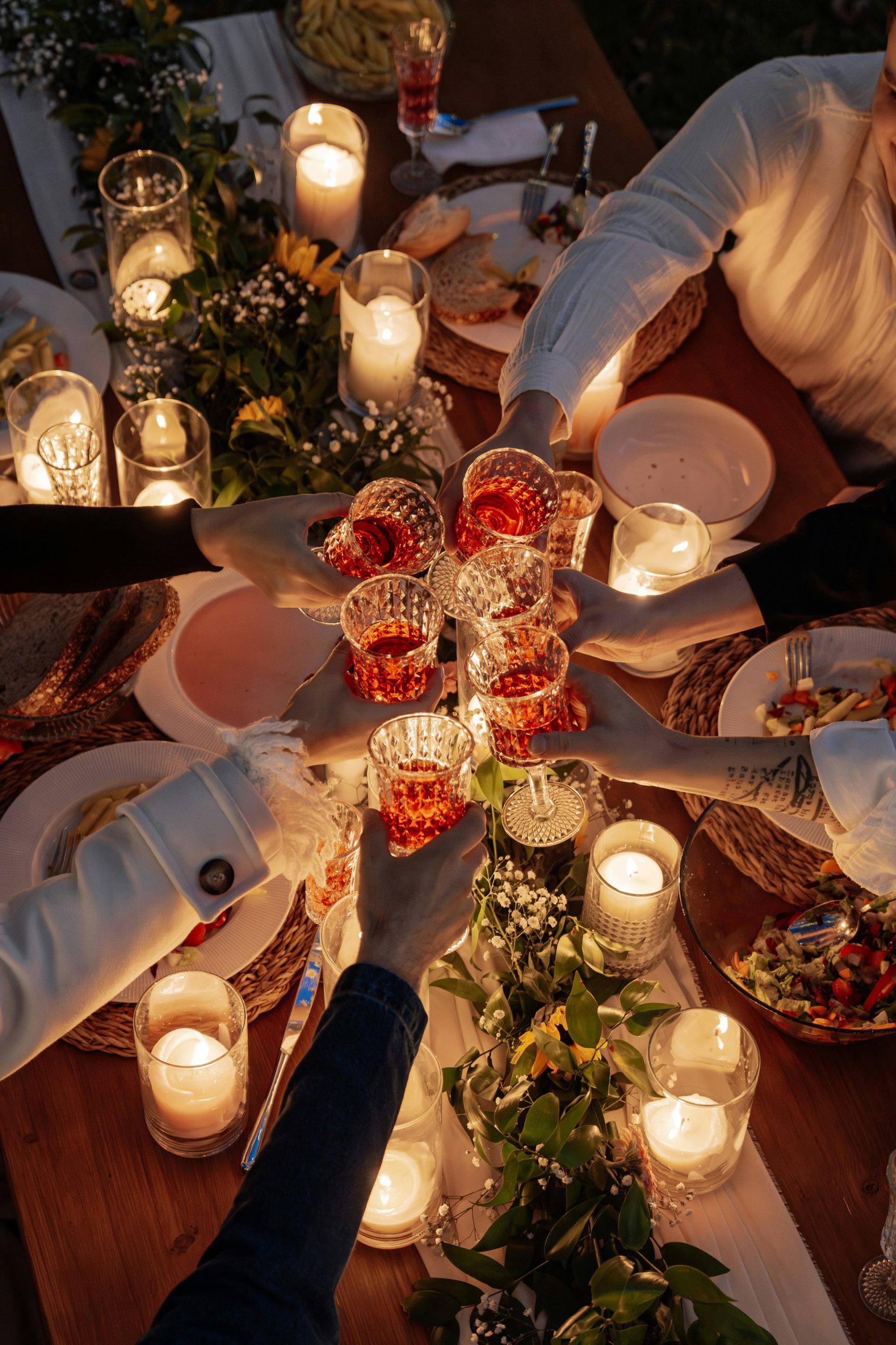 Friends and family raising glasses in a toast over a beautifully decorated candlelit table, celebrating and honouring a loved one at a living funeral gathering.