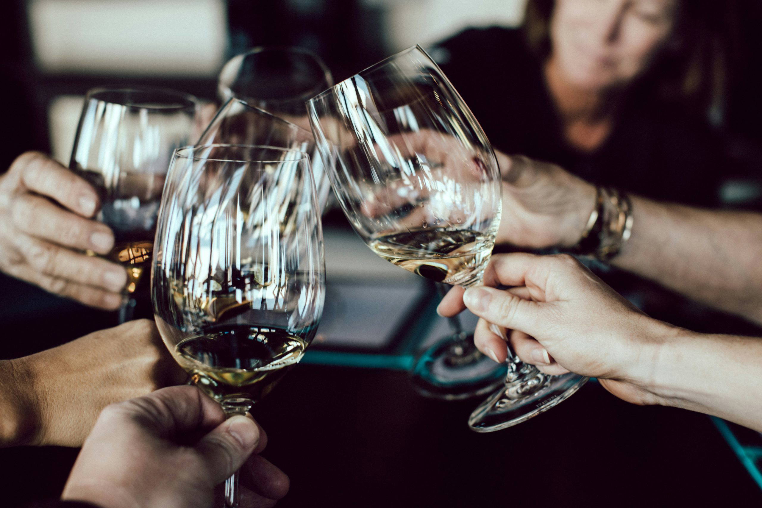 A group of people raising glasses of wine in a toast, celebrating and honouring a life together at a wake or memorial gathering.