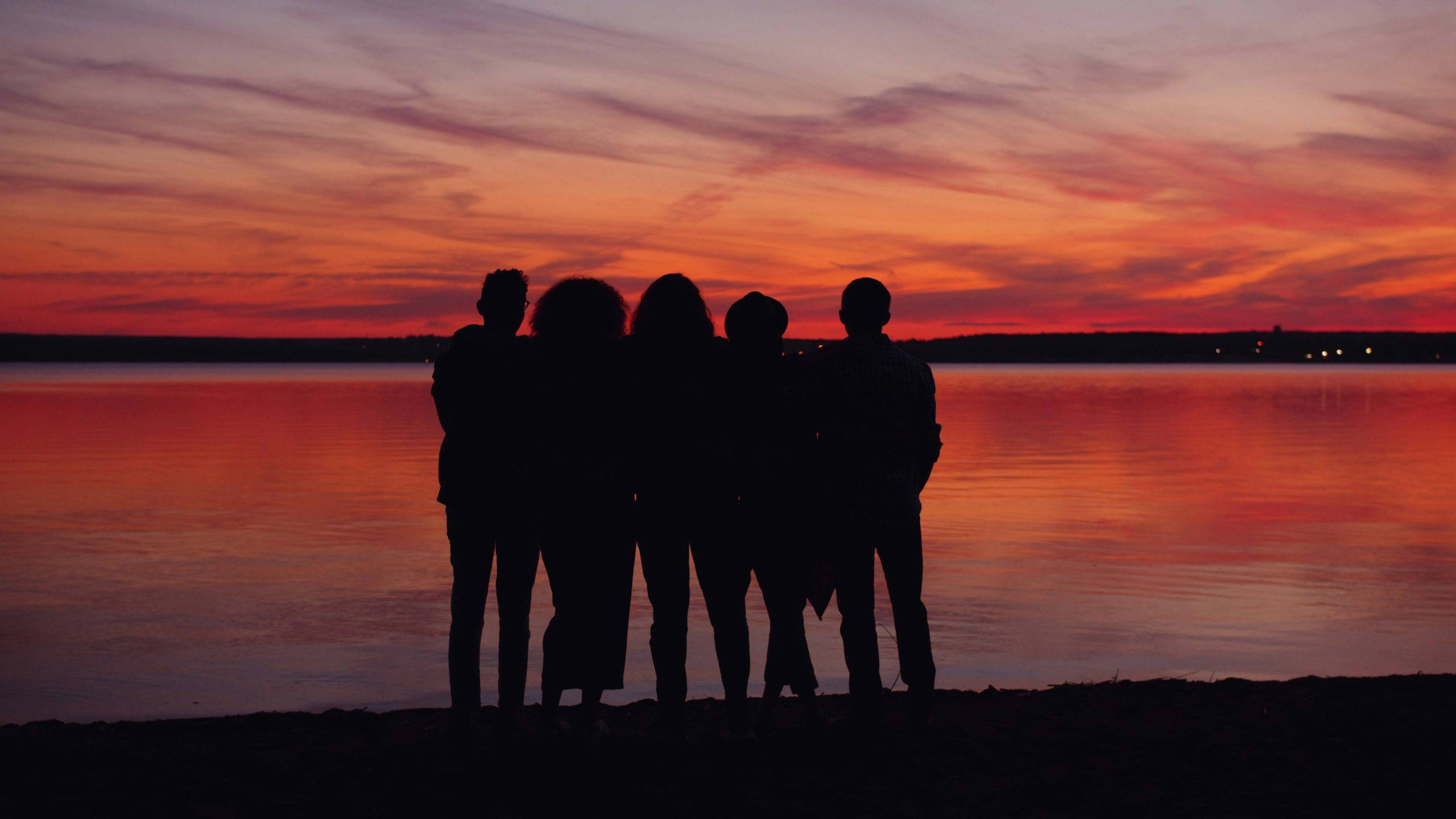An image of a group of people staring out into the sunset.